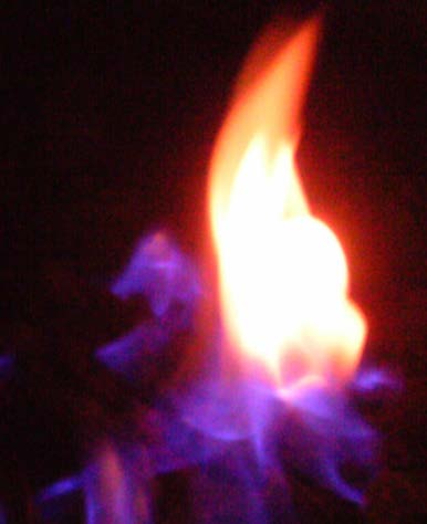 Flame image associated with Stephen Wolters, The Fireplace Guy: an orange and yellow gas flame surrounded by blue and violet flame against a dark background